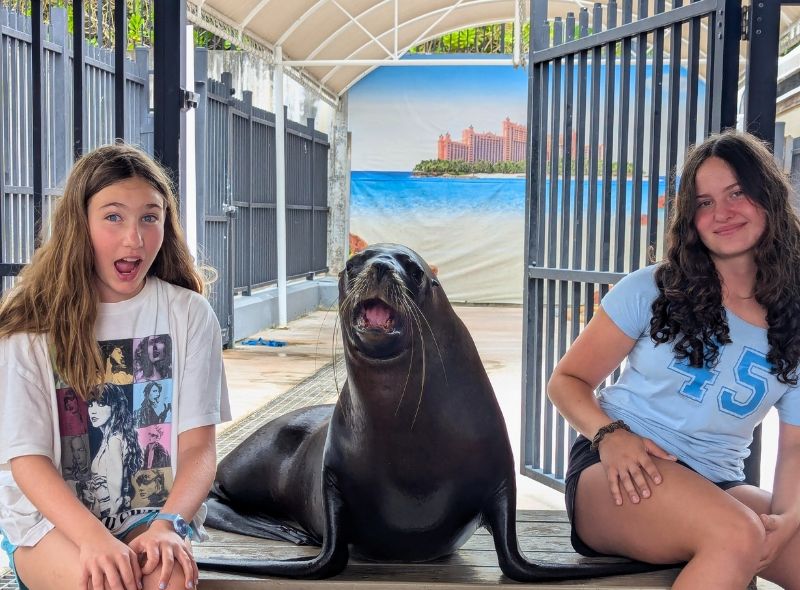 two middle school students sit with a sea lion on Bahamas marine biology camp