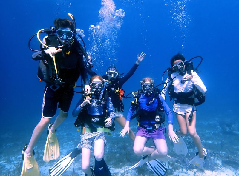 group of middle school student divers underwater on scuba and marine biology summer camp