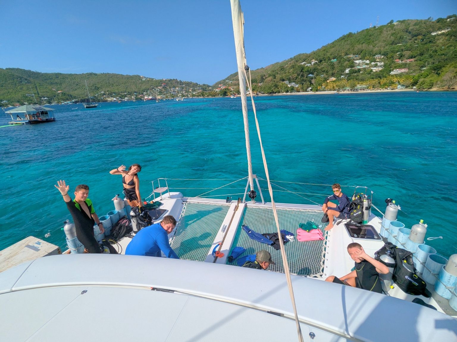 Teen students aboard a catamaran preparing scuba gear in turquoise waters near Bequia in the Caribbean