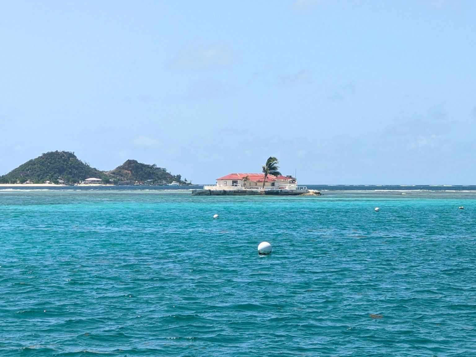 Colorful Happy Island bar with red roof in turquoise waters of Clifton Harbour, Union Island, Caribbean